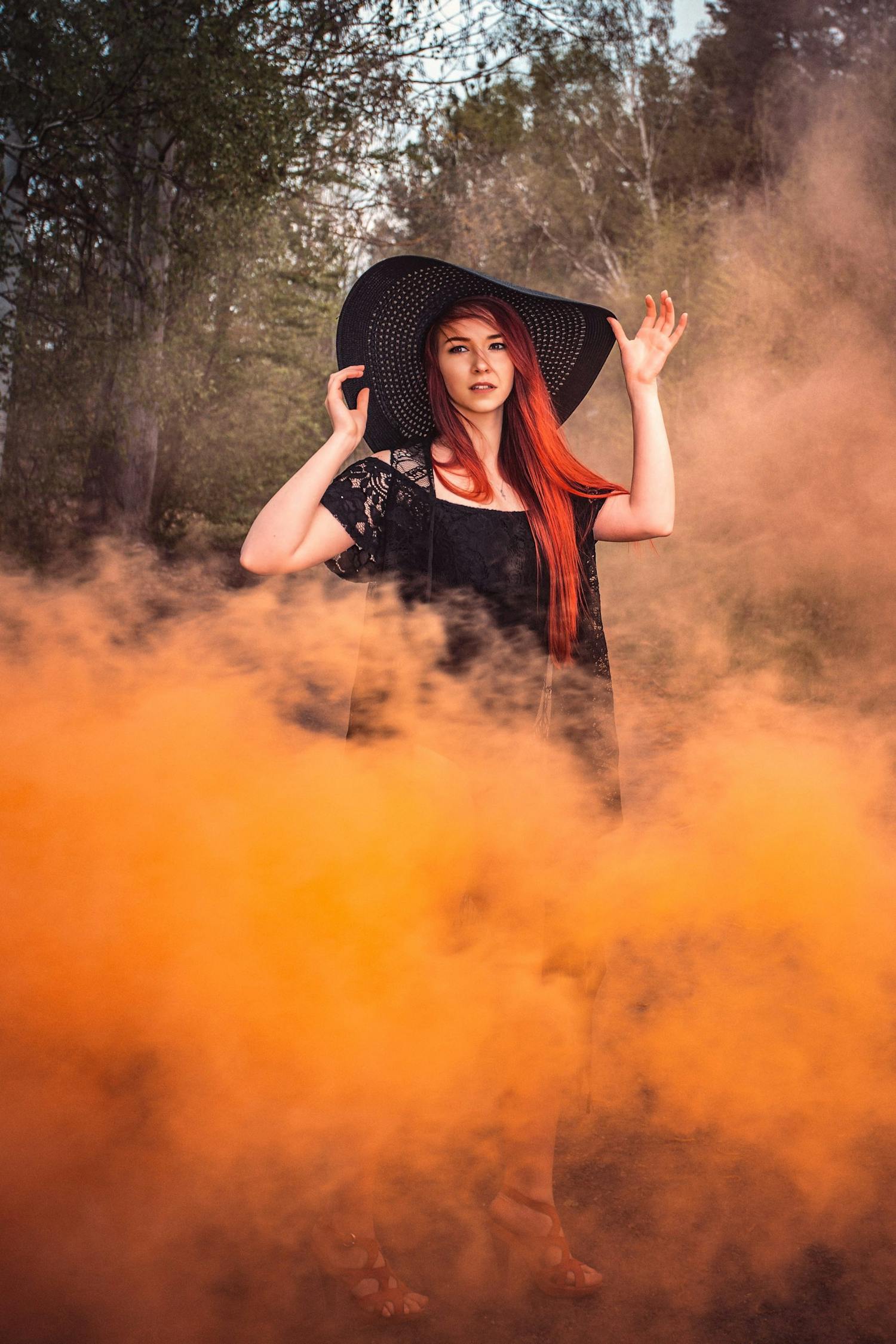 Portrett av kvinne med hatt i oransje røyk